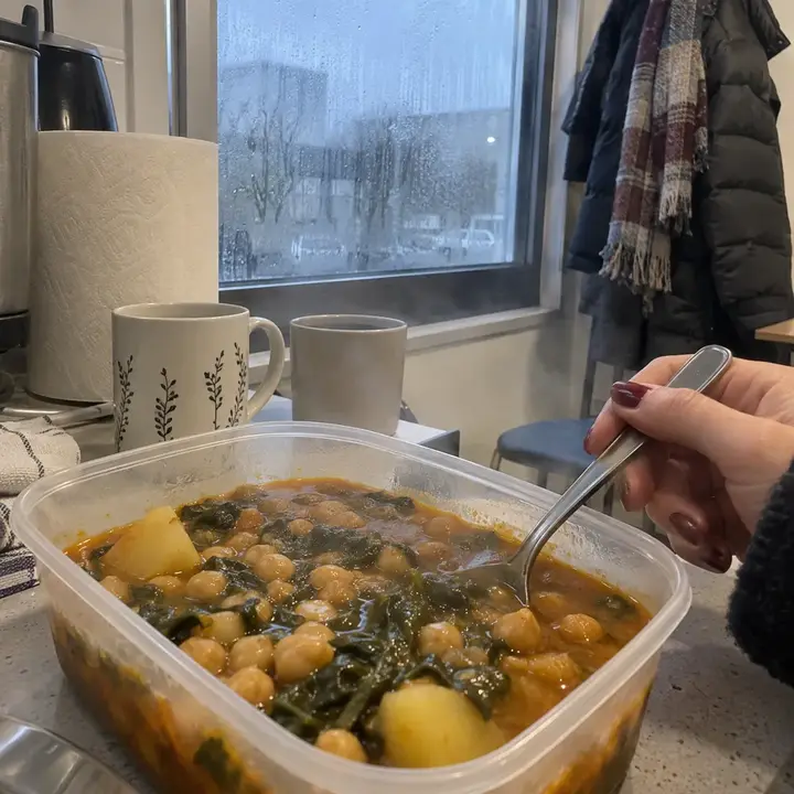 Táper de potaje de garbanzos humeante en la cocina de una oficina, un día de invierno